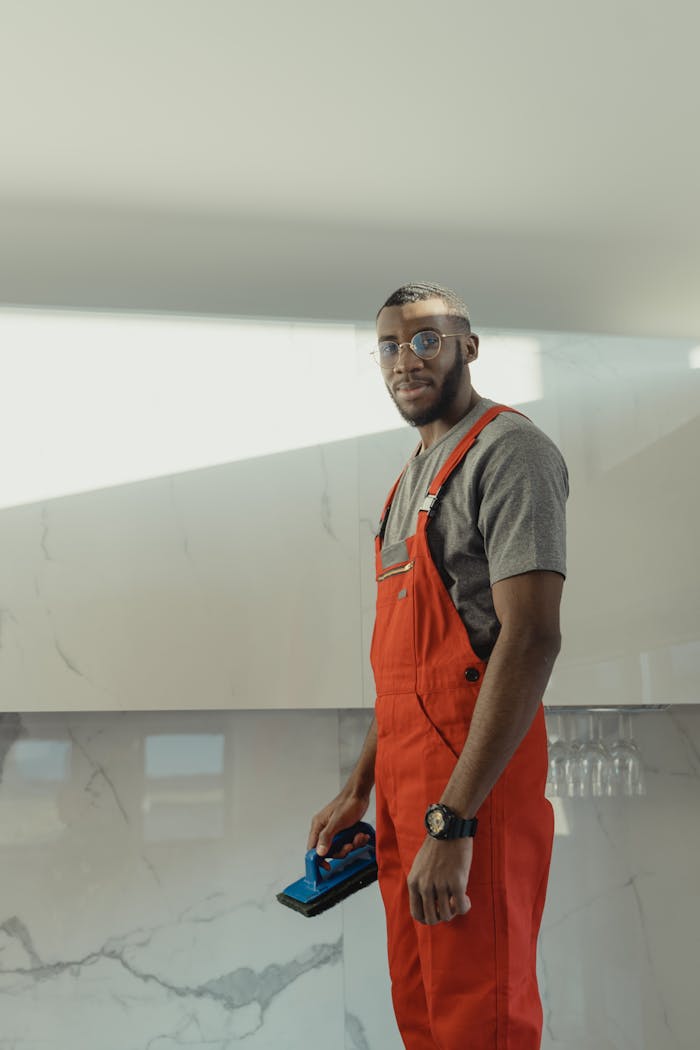 Crafting Captivating Headlines: Your awesome post title goes here Indoor photo of a man in red overalls and glasses holding a cleaning brush, standing confidently.